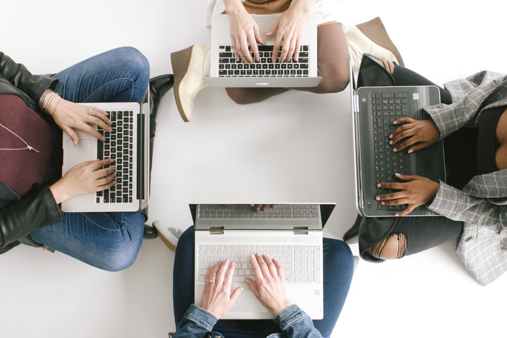 four people sitting in a circle with their laptops