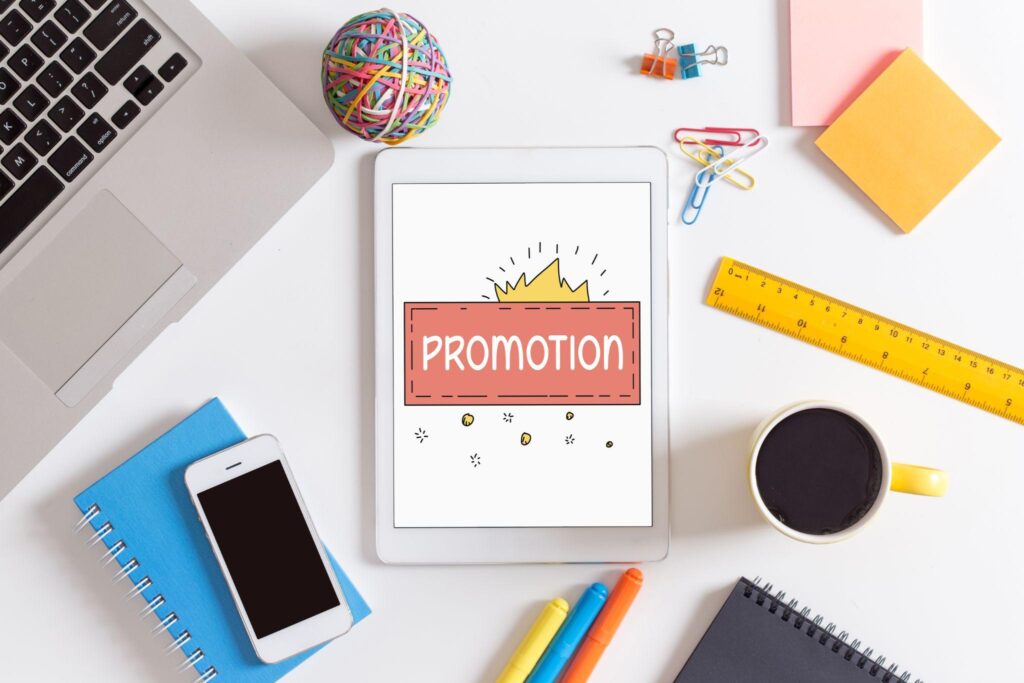 office supplies, computer, ipad, coffee mug; word "promotion" is on the ipad screen