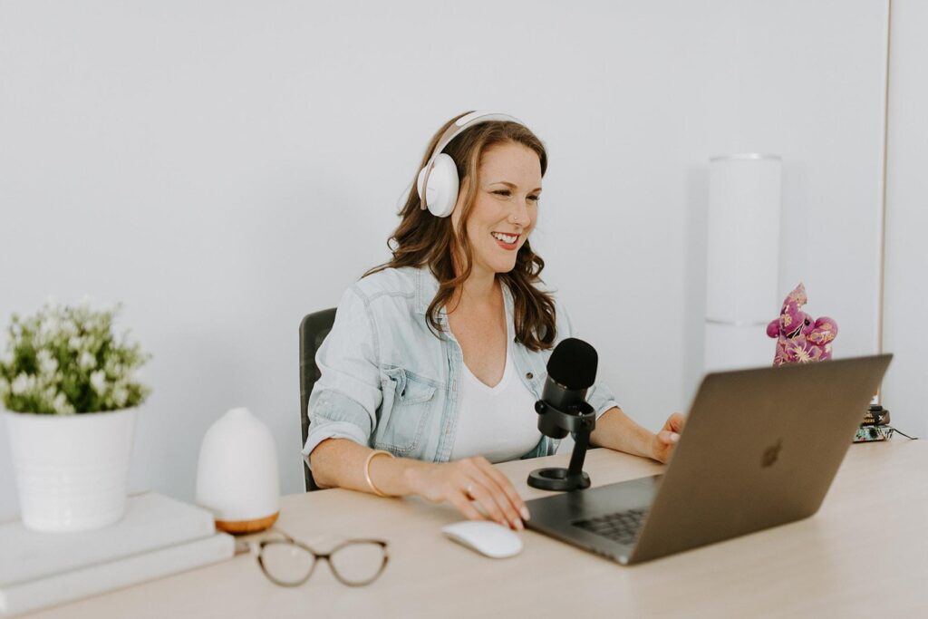 image of Rachel Harrison-Sund wearing headphones and sitting in front of a laptop and microphone