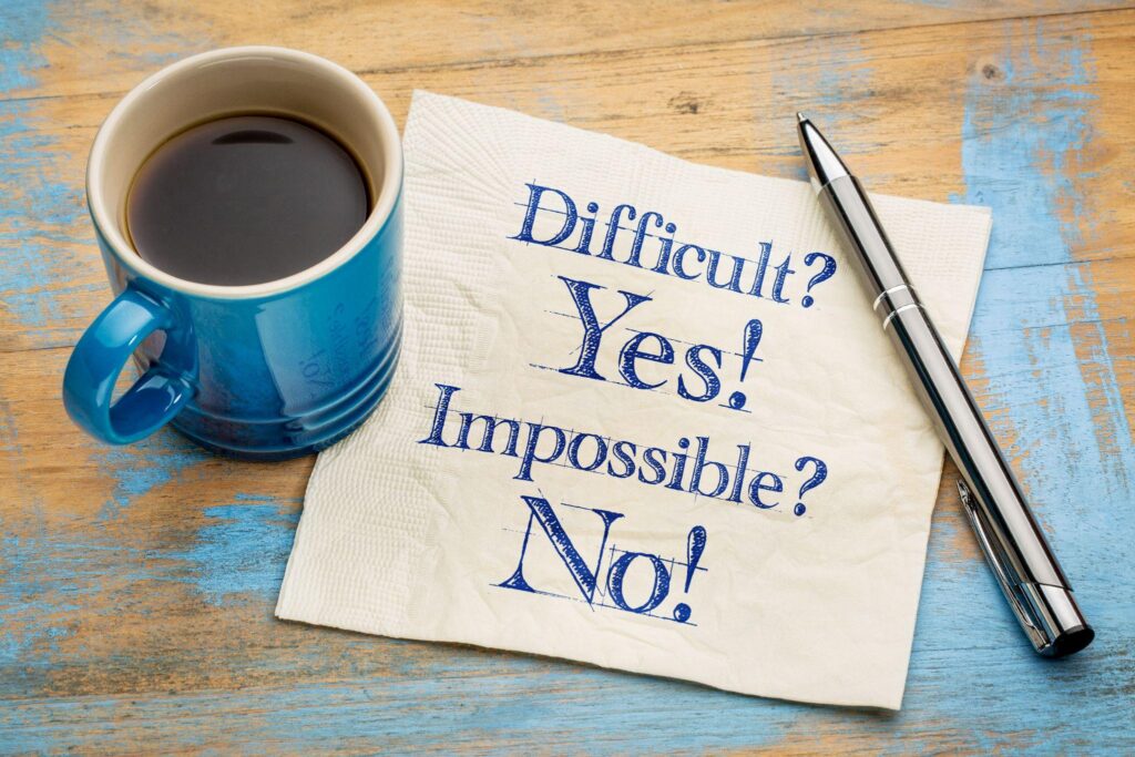 coffee cup next to a paper with the words "Difficult? Yes! Impossible? No!"