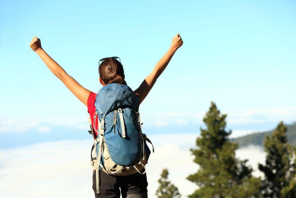 woman wearing a backpack, with her arms raised