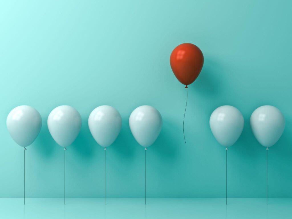 a line of balloons -- from left to right, 4 light blue balloons, one red balloon higher than the rest, and the two more light blue balloons