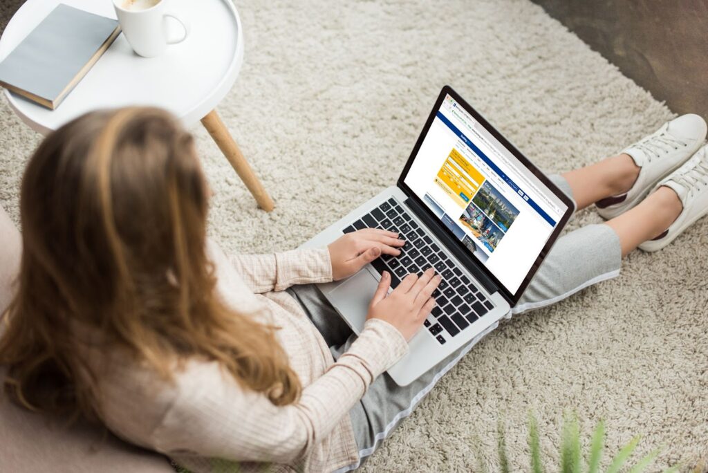 woman sitting on the floor typing on a laptop in her lap