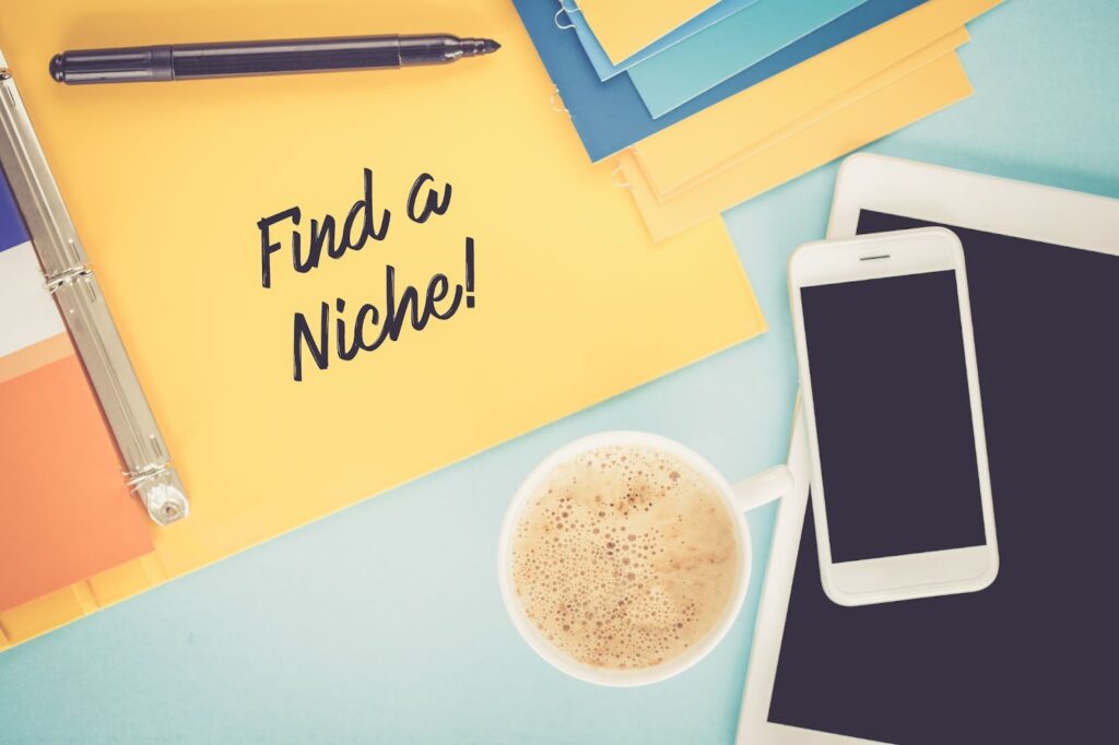 binder, black marker, cup of coffee, iphone, ipad. "Find a niche" written on binder