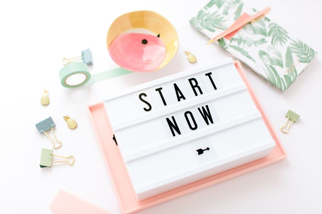 miscellaneous office supplies scattered around a calendar pad with the words "Start Now" on it