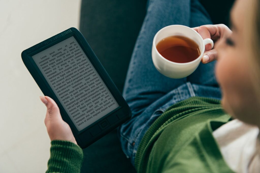 woman reading on a e-reader and holding a cup of tea