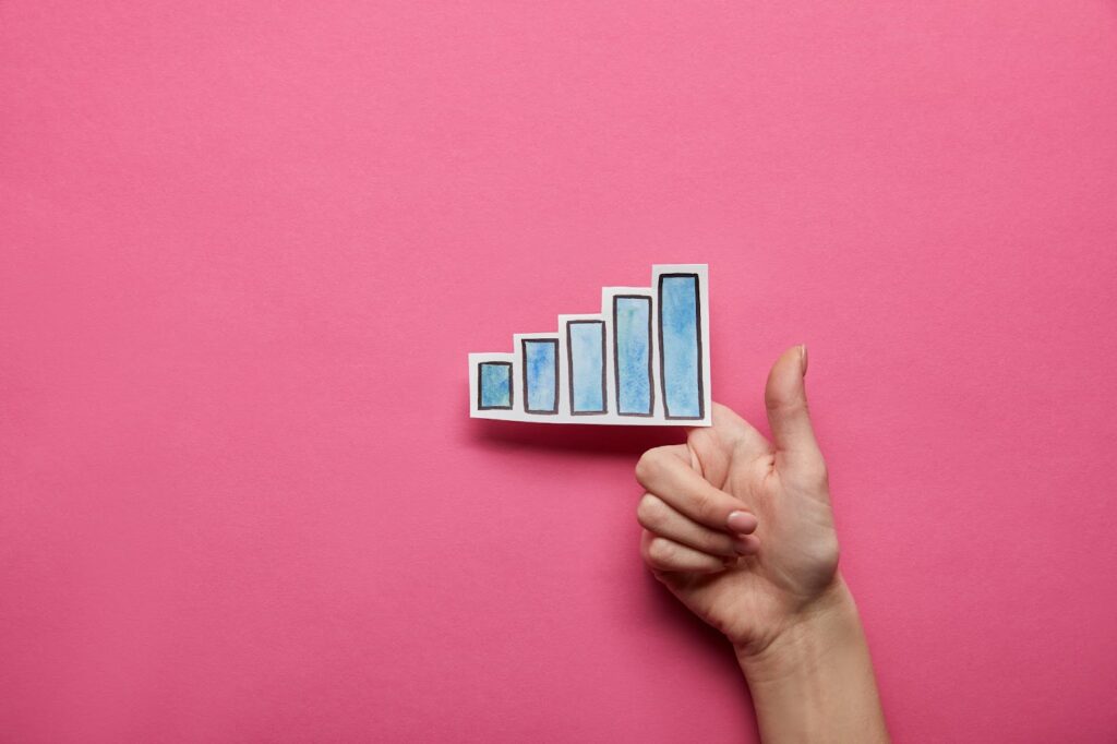 hand holding a post-it in the shape of a bar chart with blue bars. Pink background